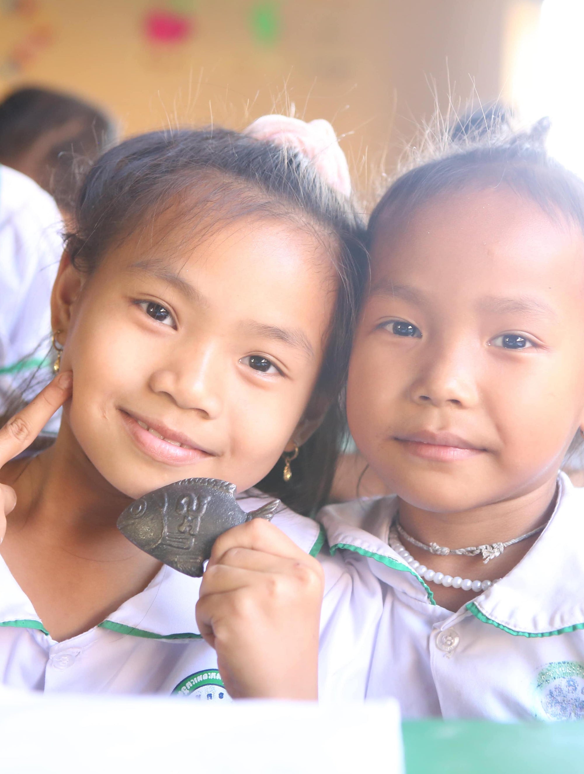 Girls holding the Lucky Iron fish in Cambodia