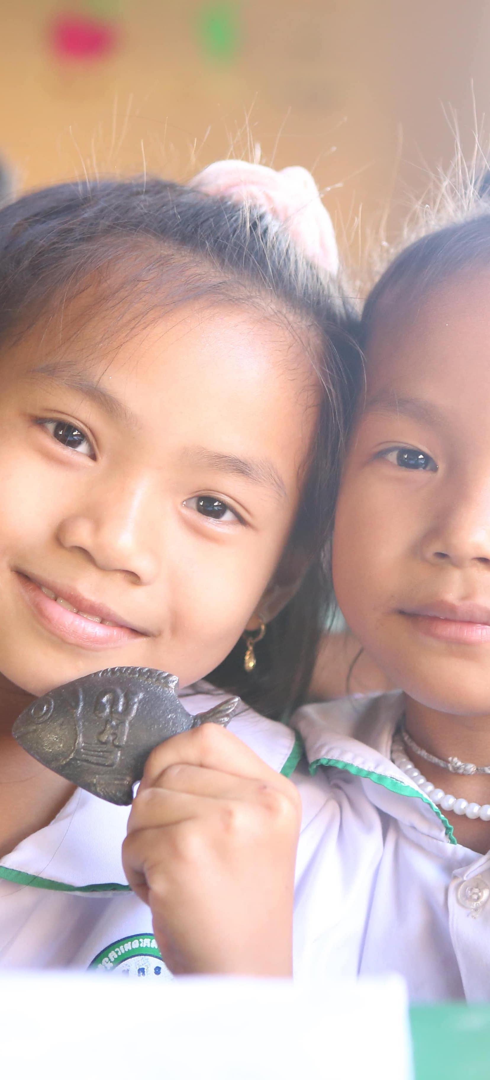 Girls holding the Lucky Iron Fish in Cambodia